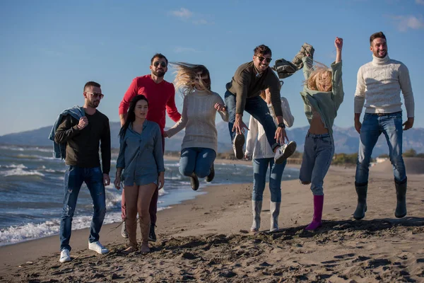 Grupo Jóvenes Amigos Emocionados Saltando Juntos Soleada Playa Otoño —  Fotos de Stock