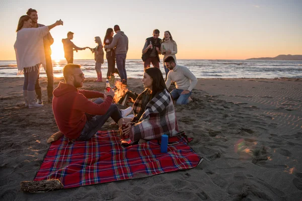 Pareja Joven Disfrutando Con Amigos Alrededor Campfire Playa Atardecer Bebiendo —  Fotos de Stock