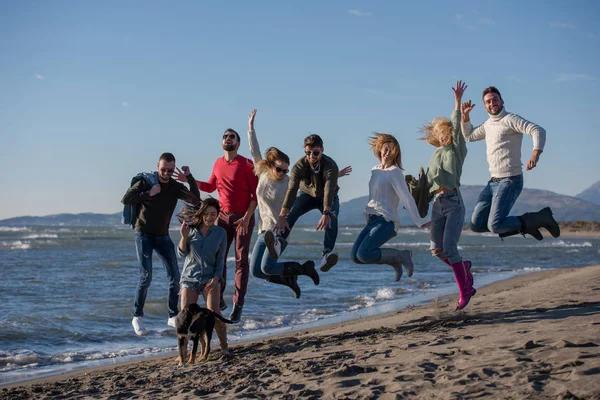 Grupo Jovens Amigos Animados Pulando Juntos Ensolarada Praia Outono — Fotografia de Stock