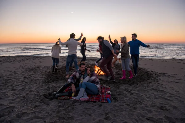 Młoda Para Zabawia Się Przyjaciółmi Przy Ognisku Plaży Zachodzie Słońca — Zdjęcie stockowe