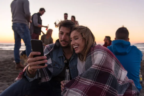 Пара Використовує Мобільний Телефон Під Час Осінньої Вечірки Пляжі Друзями — стокове фото