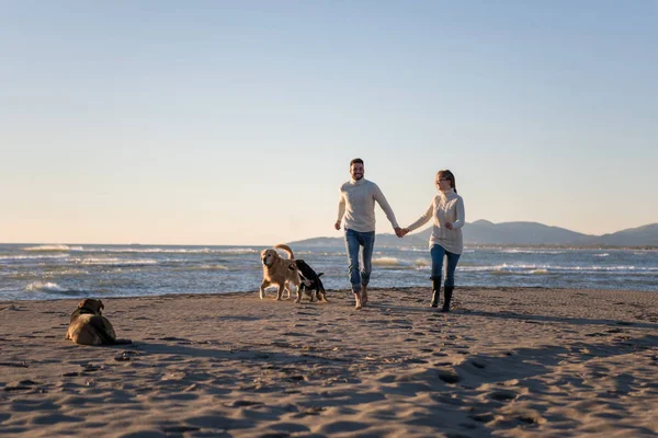 犬と手をつないでビーチを走るカップル秋の日 — ストック写真