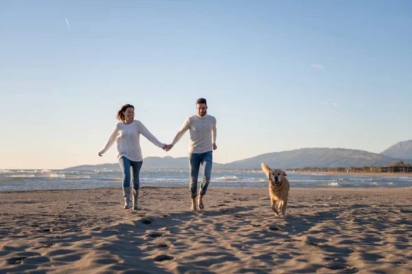 Pareja Corriendo Playa Sosteniendo Sus Manos Con Perro Día Autmun —  Fotos de Stock