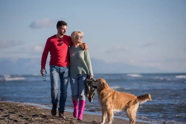 在秋天的日子里 情侣们牵着狗在海滩上奔跑 — 图库照片