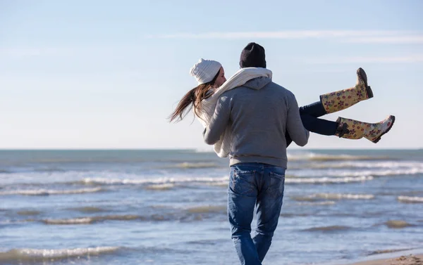秋日阳光明媚的日子里 年轻夫妇在海滩上散步和拥抱 玩得很开心 — 图库照片