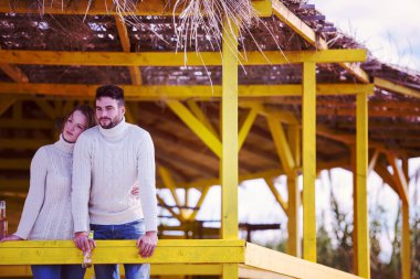 Sonbahar boyunca boş sahil barında birlikte bira içen çift.