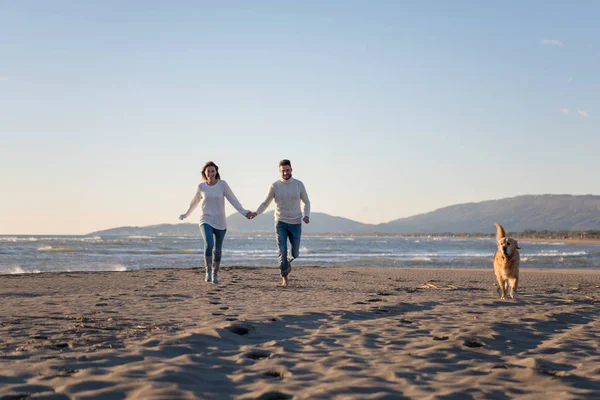 Pareja Corriendo Playa Sosteniendo Sus Manos Con Perro Día Autmun —  Fotos de Stock