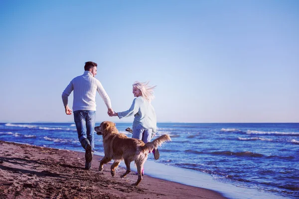 犬と手をつないでビーチを走るカップル秋の日 — ストック写真