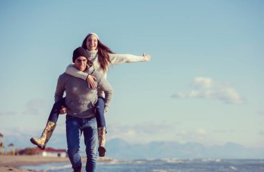 Erkekler Piggy 'i sırtında taşıyor sevgilisini Deniz kenarında, sonbahar zamanı