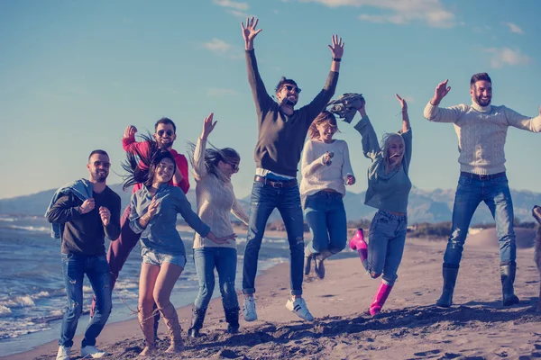 Grupa Podekscytowanych Młodych Przyjaciół Skaczących Razem Słonecznej Jesiennej Plaży — Zdjęcie stockowe