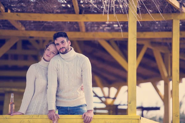 Sonbahar boyunca boş sahil barında birlikte bira içen çift.