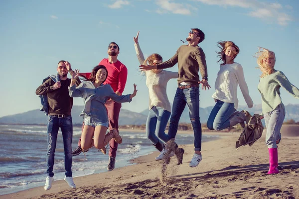 Grupo Jóvenes Amigos Emocionados Saltando Juntos Soleada Playa Otoño — Foto de Stock