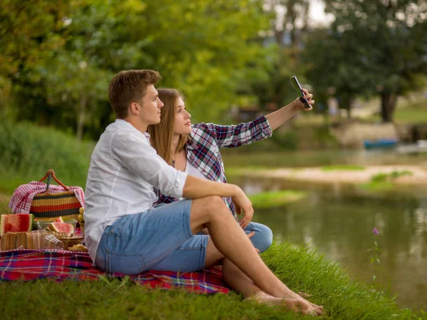 피크닉 음료와 강둑에 자연에서 음식을 즐기면서 전화는 Selfie를 복용에 — 스톡 사진