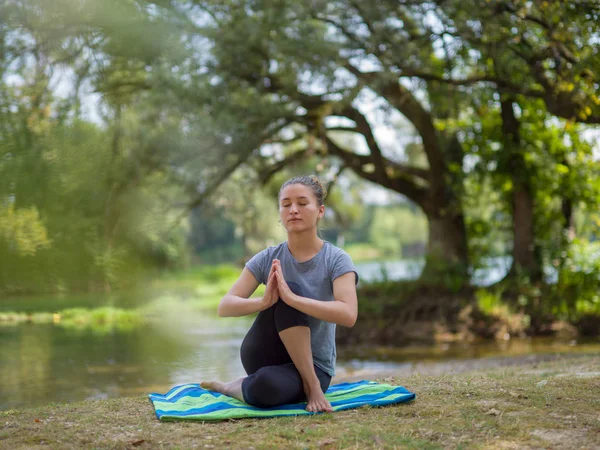 健康的妇女放松 而冥想和做瑜伽运动在美丽的自然在河岸上 — 图库照片