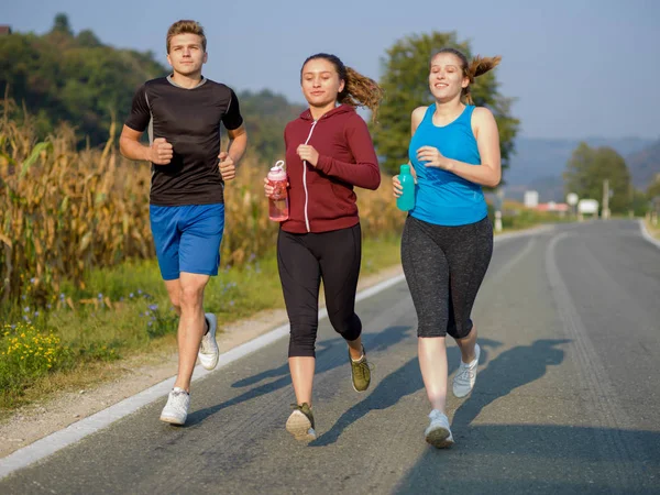 Grupa Młodych Ludzi Jogging Podismo Drogowego Kraju Działa Otwartej Drodze — Zdjęcie stockowe