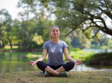 sağlıklı kadın meditasyon ve yoga yaparken Nehri kıyısında güzel doğada egzersiz yaparken rahatlatıcı