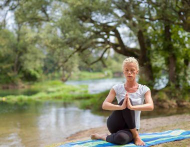 sağlıklı kadın meditasyon ve yoga yaparken Nehri kıyısında güzel doğada egzersiz yaparken rahatlatıcı