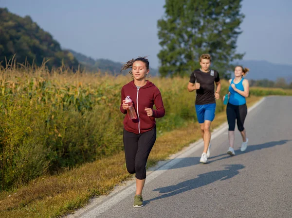 夏の日に開いている道路上で実行国道ランナー ジョギング若い人たちのグループ — ストック写真