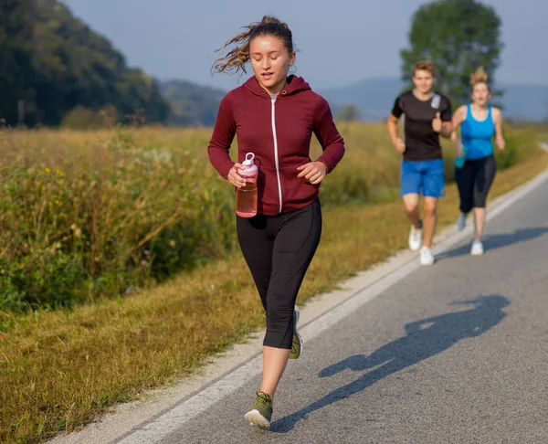 夏の日に開いている道路上で実行国道ランナー ジョギング若い人たちのグループ — ストック写真