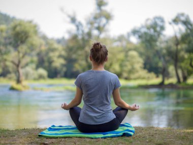 sağlıklı kadın meditasyon ve yoga yaparken Nehri kıyısında güzel doğada egzersiz yaparken rahatlatıcı