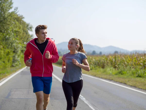 年轻夫妇享受慢跑沿着乡间小路在上午 — 图库照片