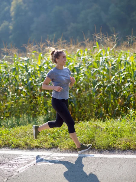 田舎でジョギングしながら健康な生活を楽しんでいる若い女性 — ストック写真