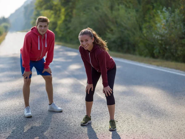 朝の国の道路に沿ってジョギングを楽しむ若いカップル — ストック写真