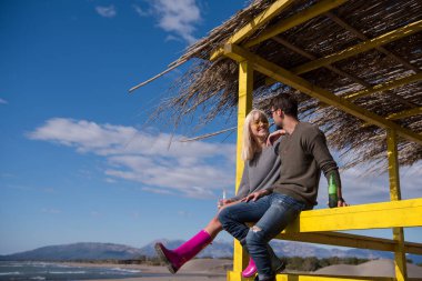 Sonbahar boyunca boş sahil barında birlikte bira içen çift.