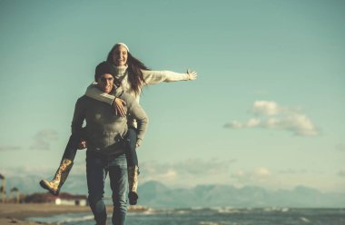 Erkekler Piggy 'i sırtında taşıyor sevgilisini Deniz kenarında, sonbahar zamanı