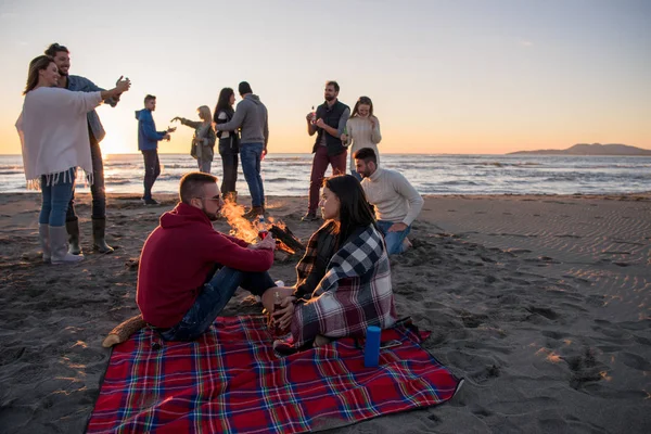 Casal Jovem Curtindo Com Amigos Redor Fogueira Praia Pôr Sol — Fotografia de Stock