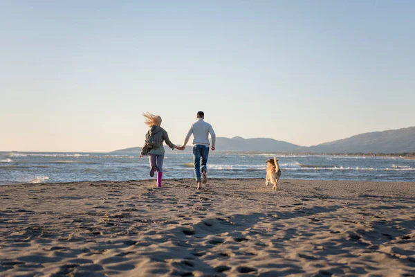 Pareja Corriendo Playa Sosteniendo Sus Manos Con Perro Día Autmun —  Fotos de Stock