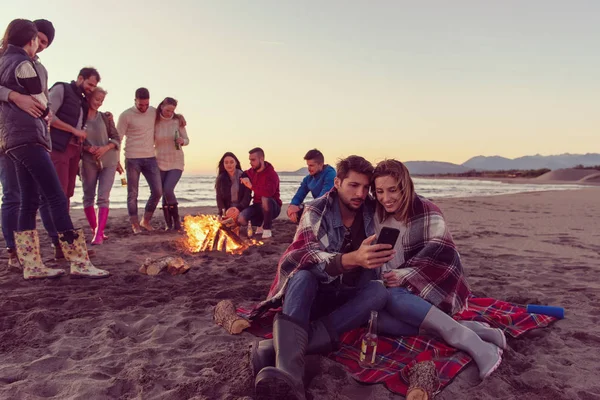 Paar Met Behulp Van Mobiele Telefoon Tijdens Herfst Strandfeest Met — Stockfoto