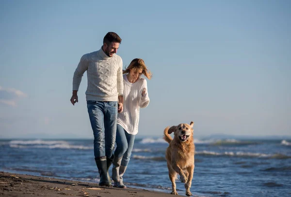 犬と手をつないでビーチを走るカップル秋の日 — ストック写真