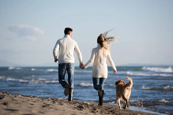 Para Biegająca Plaży Trzymająca Się Ręce Psem Dniu Autmun — Zdjęcie stockowe