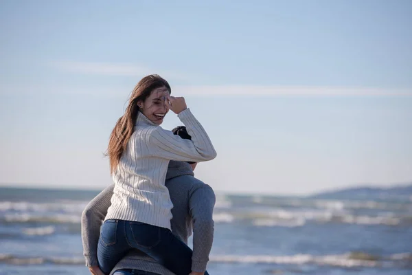 男はピギーバックを与える海で日没で彼のガールフレンドに乗る 秋の時間 — ストック写真