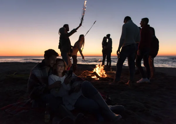 Couple Using Cell Phone Autumn Beach Party Friends Drinking Beer — Stock Photo, Image