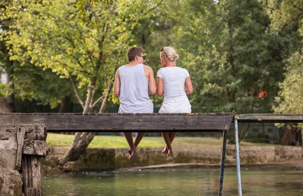 情侣在爱享受西瓜 而坐在木桥过河在美丽的自然 — 图库照片