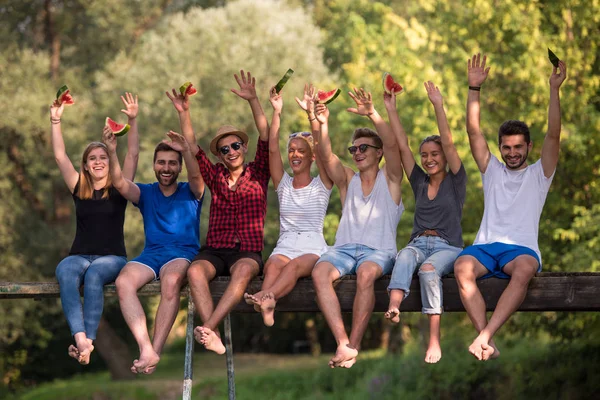 Gruppo Giovani Amici Godendo Anguria Mentre Seduto Sul Ponte Legno — Foto Stock