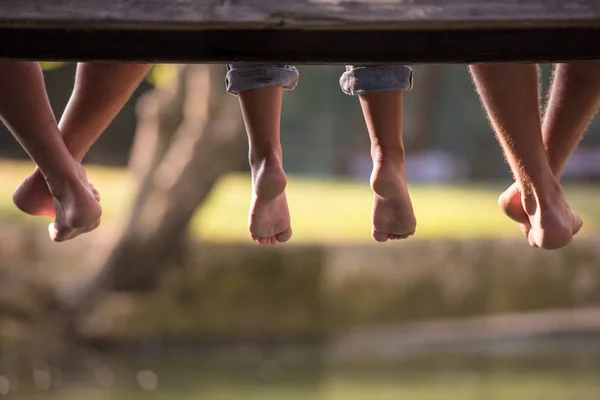 Voeten Van Mensen Zitten Houten Brug Rivier — Stockfoto