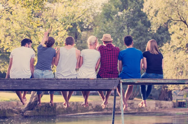 Groep Jonge Vrienden Zitten Houten Brug Rivierwater — Stockfoto