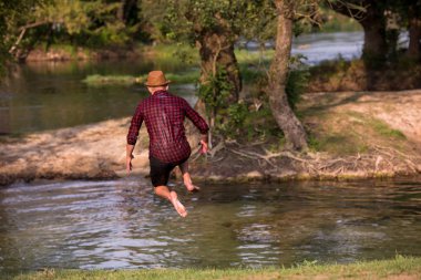 Mutlu adam eğleniyor giysilerle nehir atlama