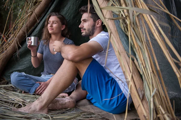 恋旅行と川で熱いお茶を飲みながらわらテントで一緒に時間を過ごすカップル — ストック写真