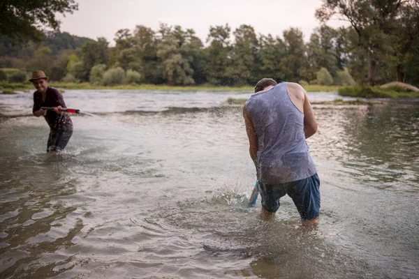 在河边溅水时 有水枪乐趣的年轻男子 — 图库照片