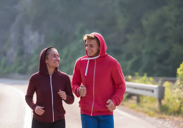 国の道路に沿って実行しているジョギングの若いカップル — ストック写真