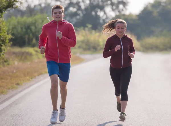 年轻夫妇享受健康的生活方式 而慢跑沿乡间小路 — 图库照片