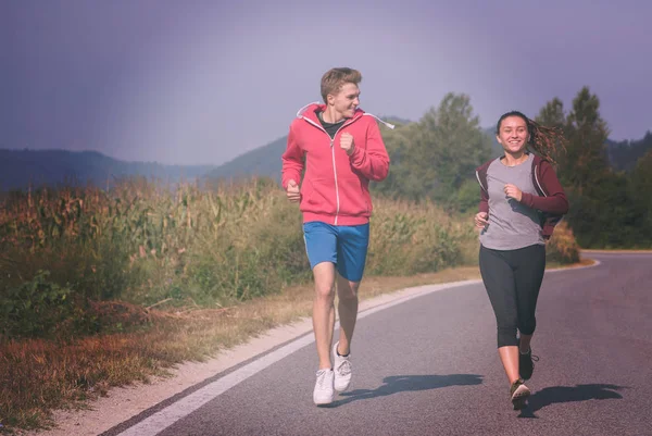 年轻夫妇享受健康的生活方式 而慢跑沿乡间小路 — 图库照片