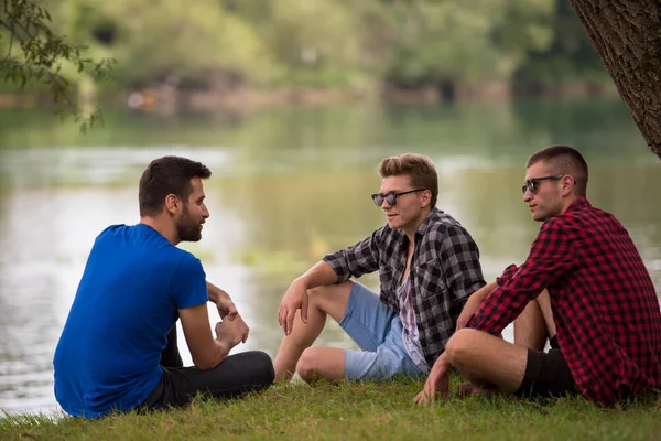Grupa Młodych Ludzi Przyrodą Siedząc Brzegu Rzeki — Zdjęcie stockowe