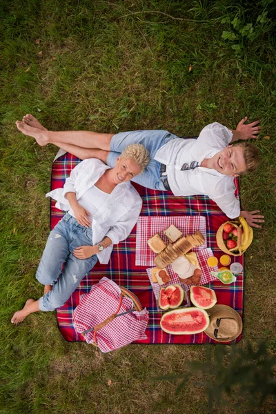 恋の格子縞に座ってピクニック時間を楽しむカップル — ストック写真