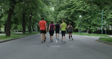 Bir grup koşucu şehir parkında birlikte koşarken arkadan görülmüş.
