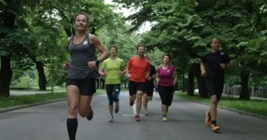 Bir grup koşucu şehir parkında birlikte koşarken arkadan görülmüş.